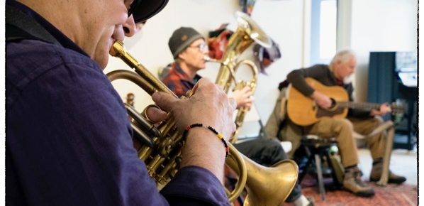 Three musicians playing their instruments in a comfortable space.