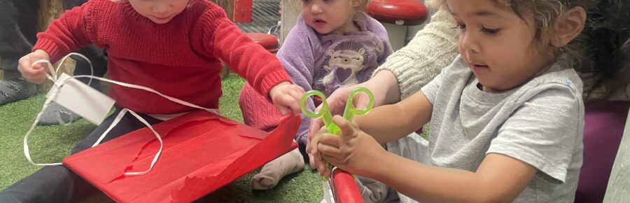Three young children opening their gifts of books from Action Read.