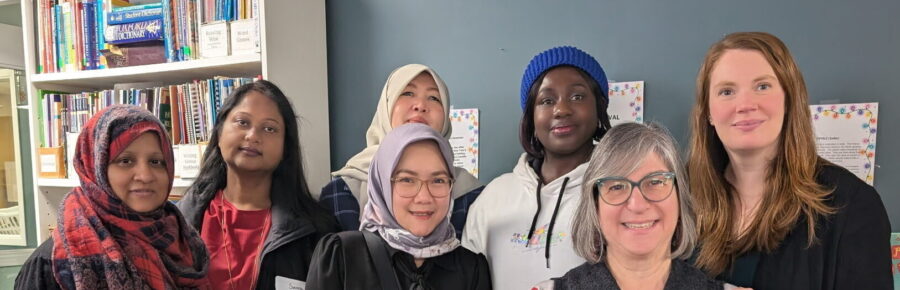A diverse group of 7 cheerful looking female learners and staff members at our annual holiday party.