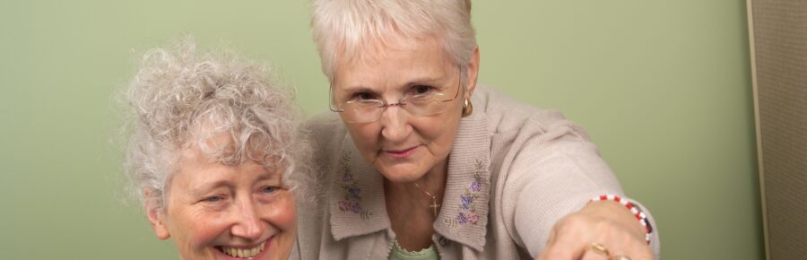 Happy tutor learner pair of women looking at a computer.