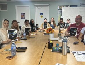 A diverse group of 11 adult learners proudly holding their books and smiling happily at the camera, celebrating their learning and achievements.