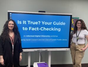Photo of two presenters standing in front of a smart board, with the words 'Is it True? Your Guide to Fact-Checking' written on it.